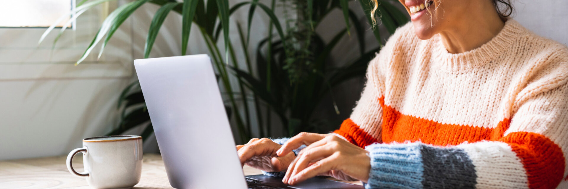 Happy woman writing on laptop on desk table in home office workplace. Adult female cheerful portrait wearing glasses and using laptop smiling. Modern alternative business job entrepreneur business, homeoffice