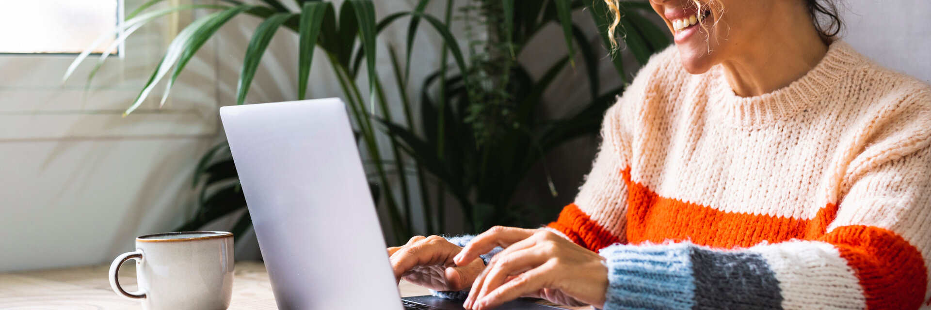 Happy woman writing on laptop on desk table in home office workplace. Adult female cheerful portrait wearing glasses and using laptop smiling. Modern alternative business job entrepreneur business, homeoffice
